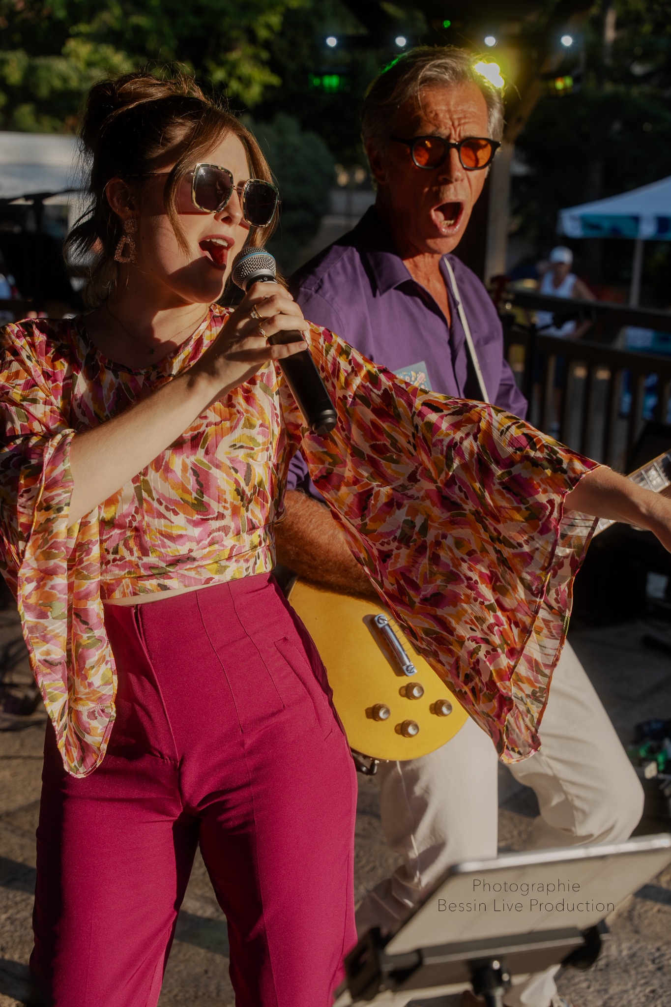Chanteuse au micro accompagnée par un guitariste lors d’un concert